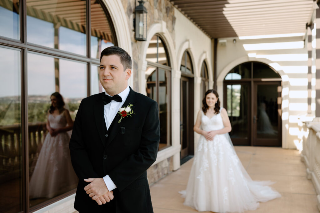 groom waiting for first look moment on the balcony